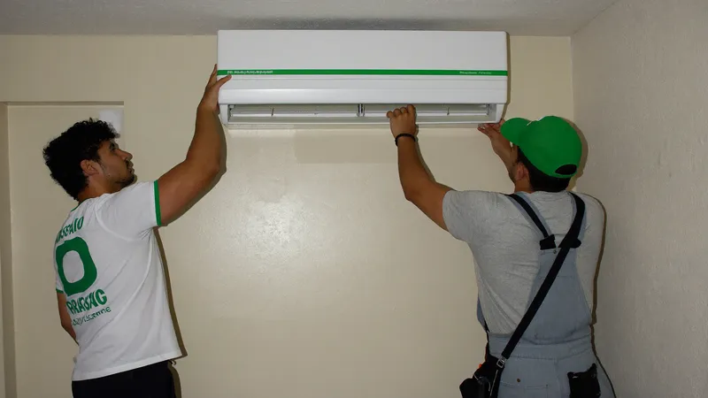 Two technicians installing a new split AC unit in an empty apartment
